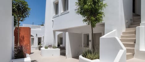 A modern white building with a staircase, outdoor seating, and potted plants.