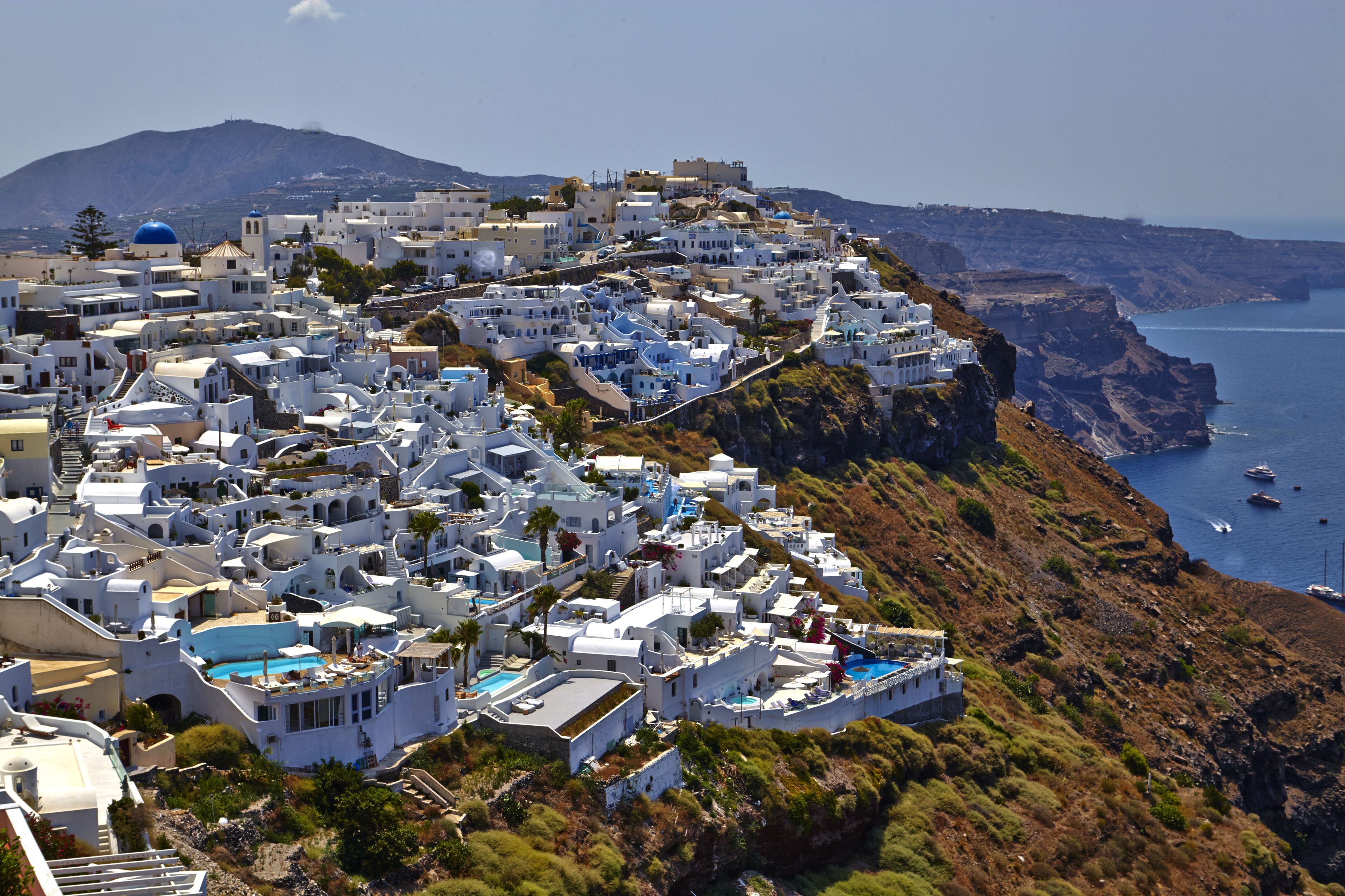 A coastal village with white buildings, a cliffside, and a view of the sea.