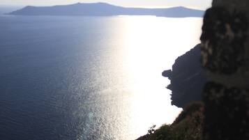 A coastal landscape with a clear sky, a body of water, and a rocky cliff.
