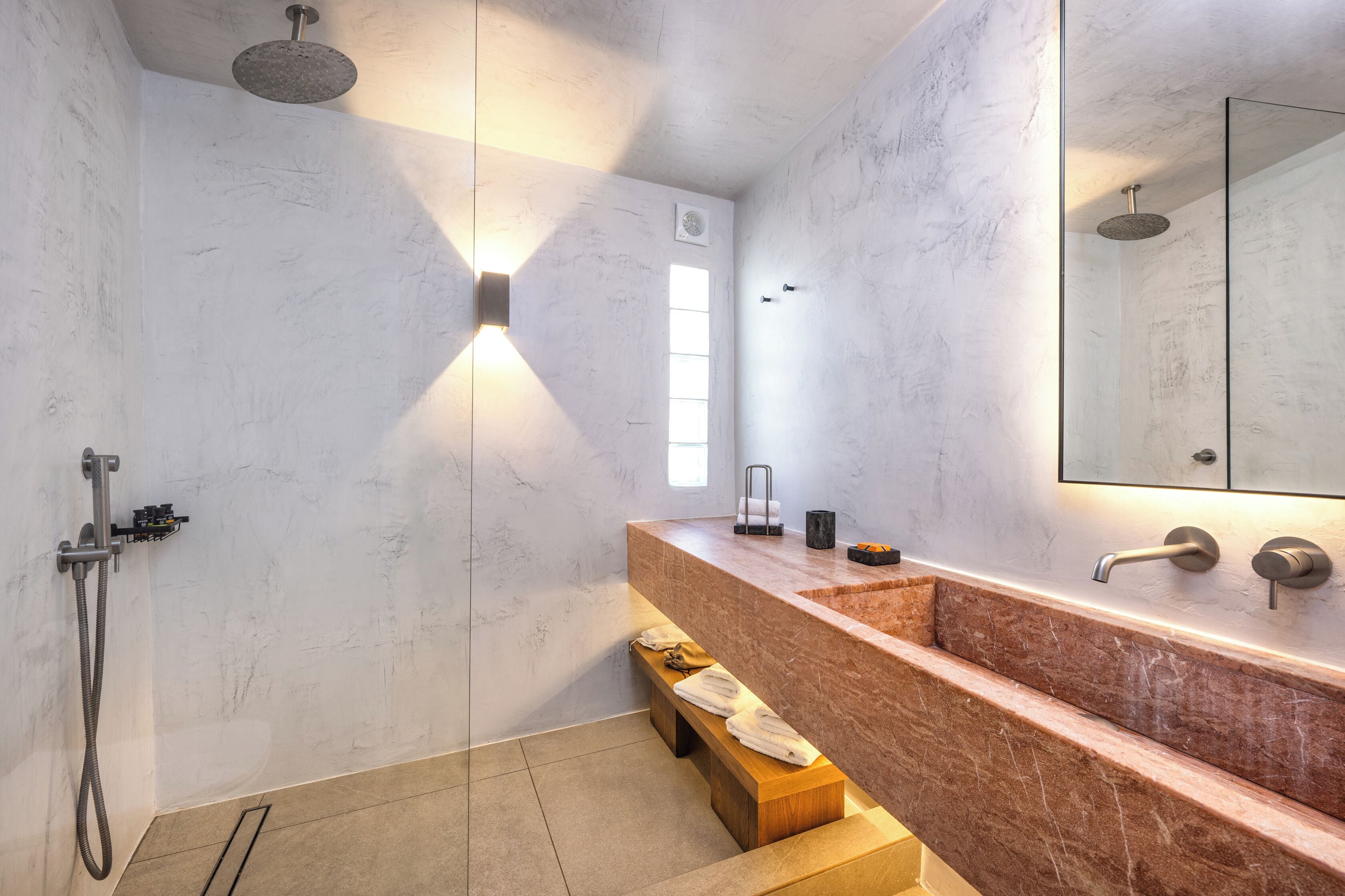 Un baño moderno con tocador de mármol, ducha y un espejo grande.