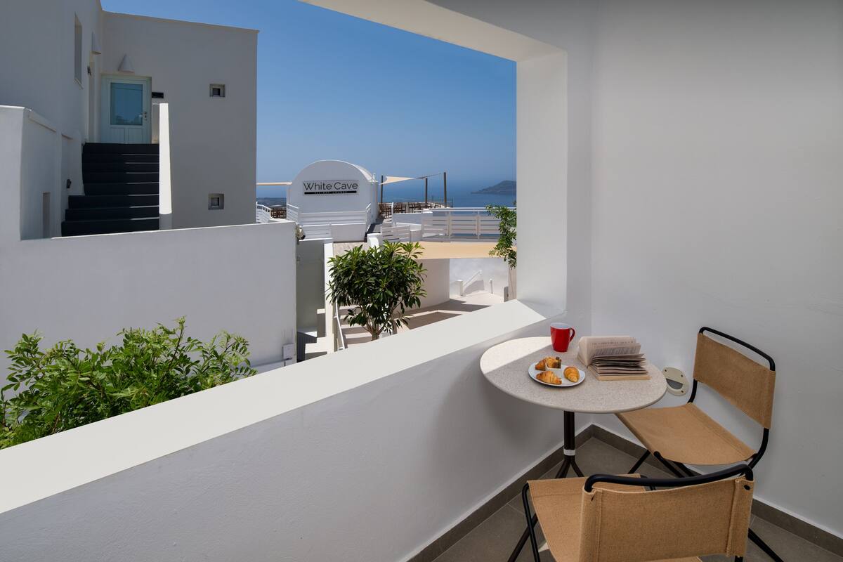 A balcony with a table, chair, and a view of the sea.