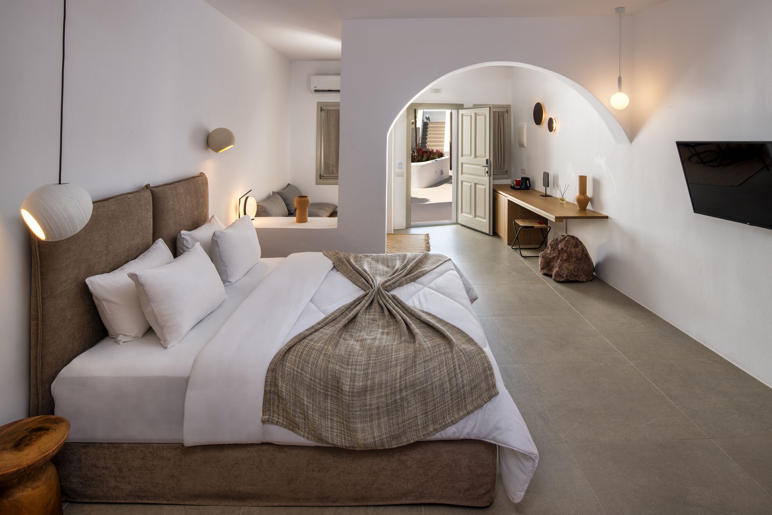 Un dormitorio moderno con una cama grande, un escritorio y un televisor.