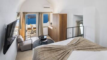 Habitación de hotel con cama, televisión, escritorio con silla, armario y vista al mar.