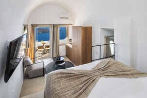 Habitación de hotel con cama, televisión, escritorio con silla, armario y vista al mar.
