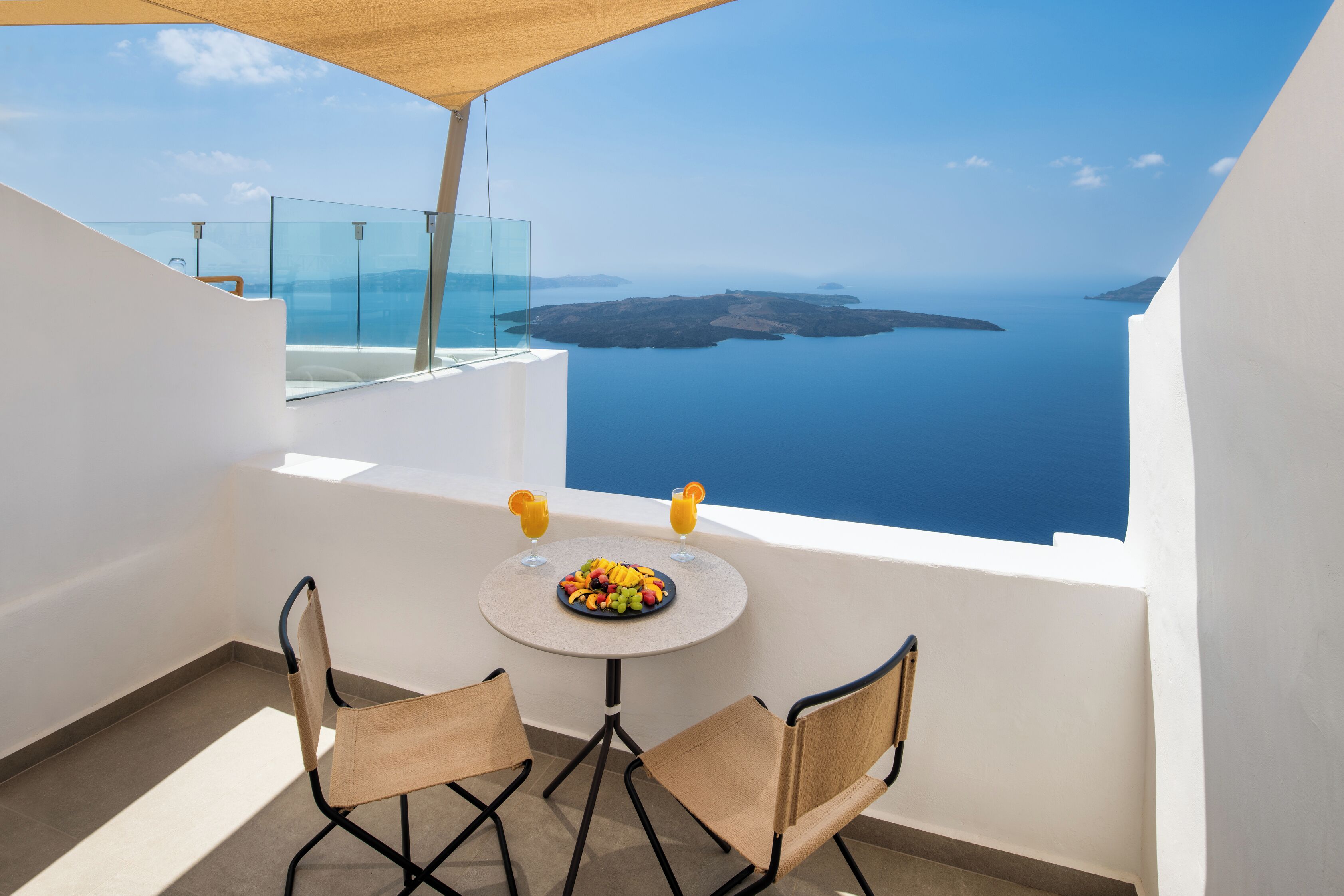 Ein Balkon mit Tisch und Stühlen, einer Glastrennwand und Blick auf das Meer.