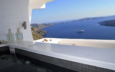 A bathtub with a view of the ocean and cliffs.