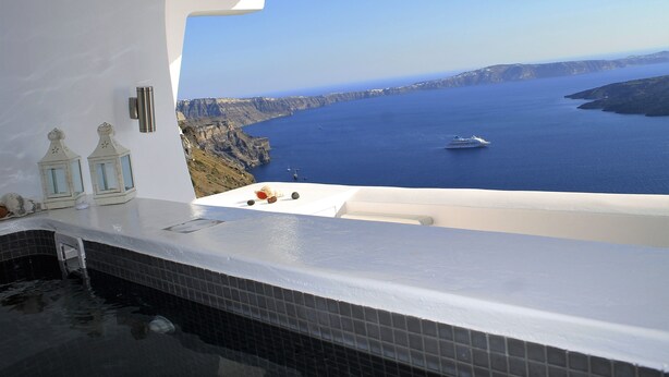 A bathtub with a view of the ocean and cliffs.
