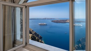 A view from a window overlooking a coastal area with a ship in the distance.