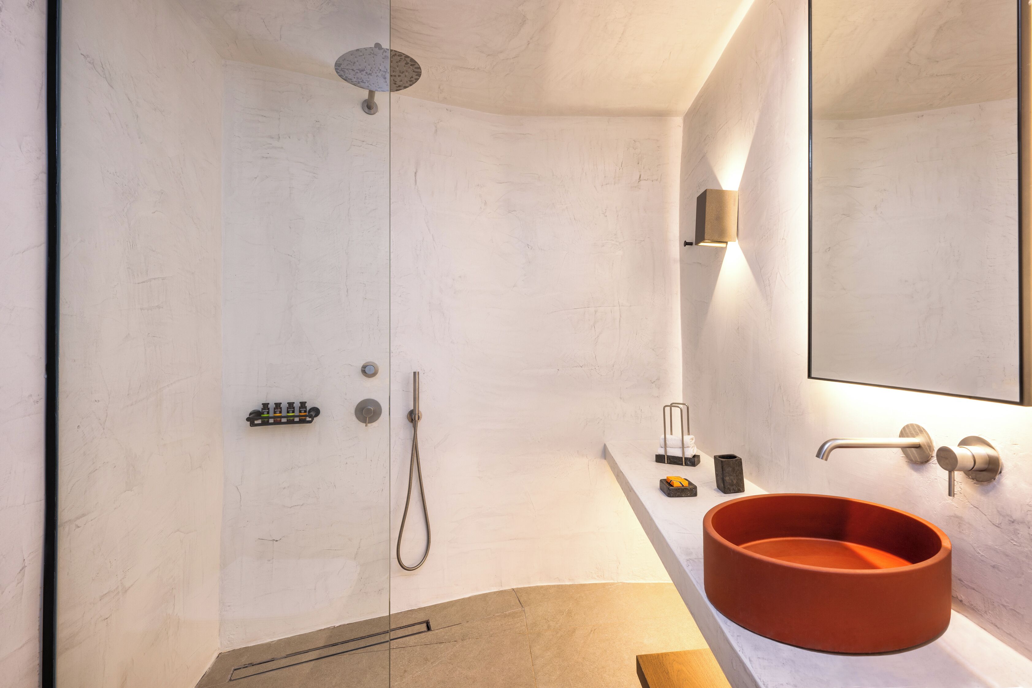 Een moderne badkamer met een grote spiegel, een rond wastafel en een douche.