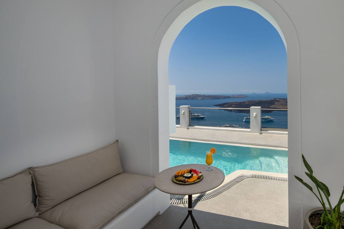 A balcony with a pool, a sofa, and a table with fruit and a drink.