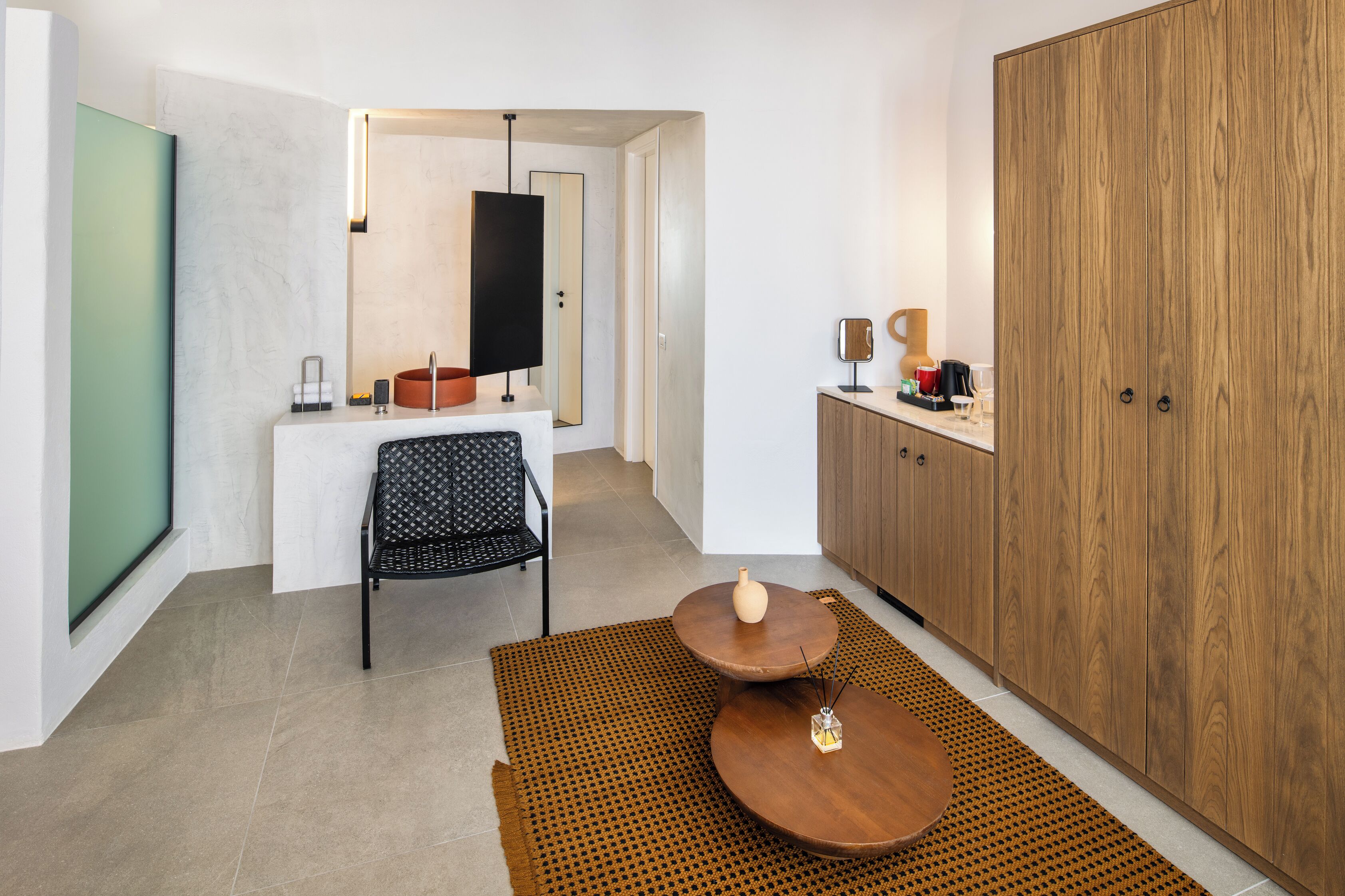 A modern kitchen with a dining area, featuring a wooden cabinet, a dining table, and a black chair.
