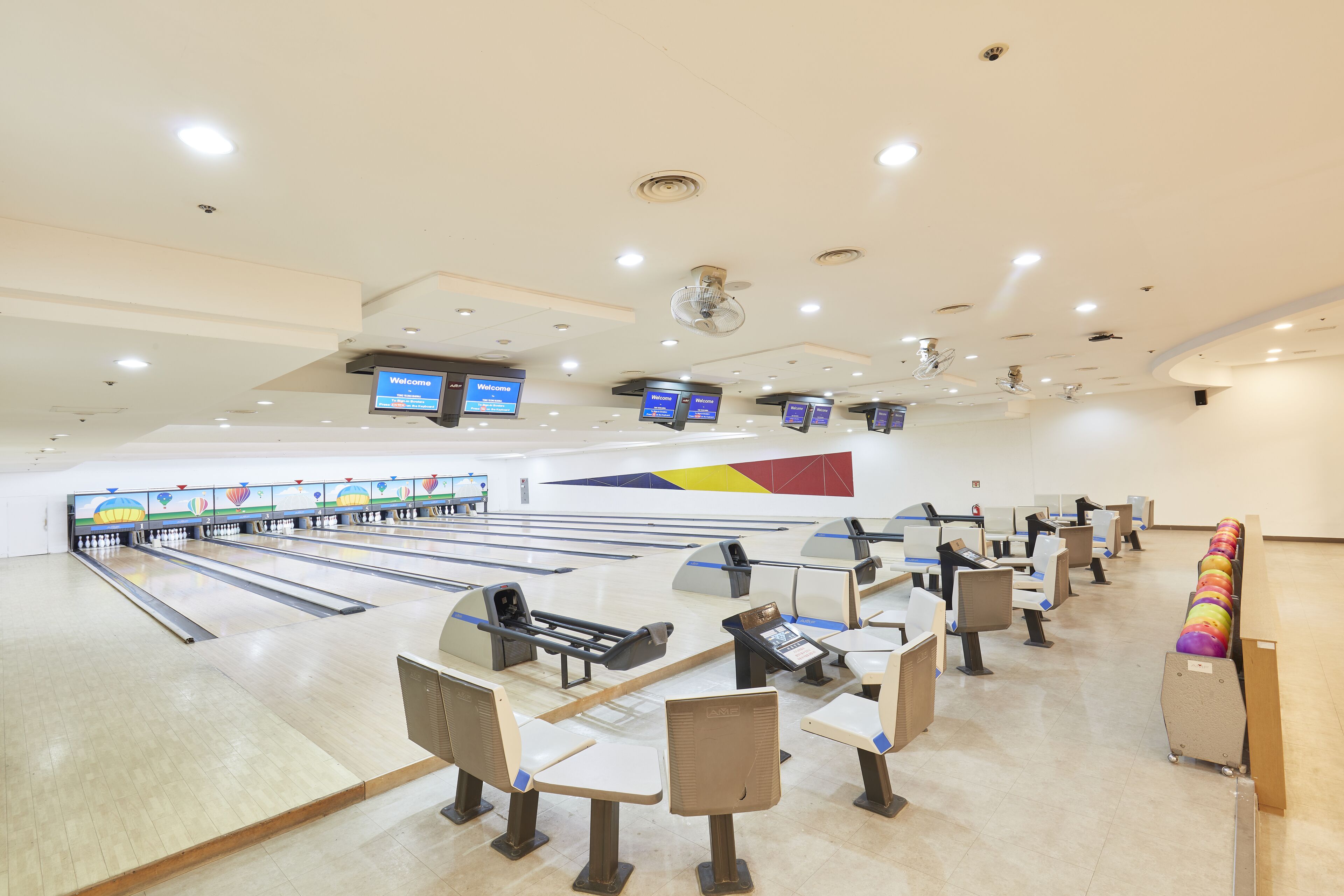 A bowling alley with multiple lanes, seating areas, and digital scoreboards.