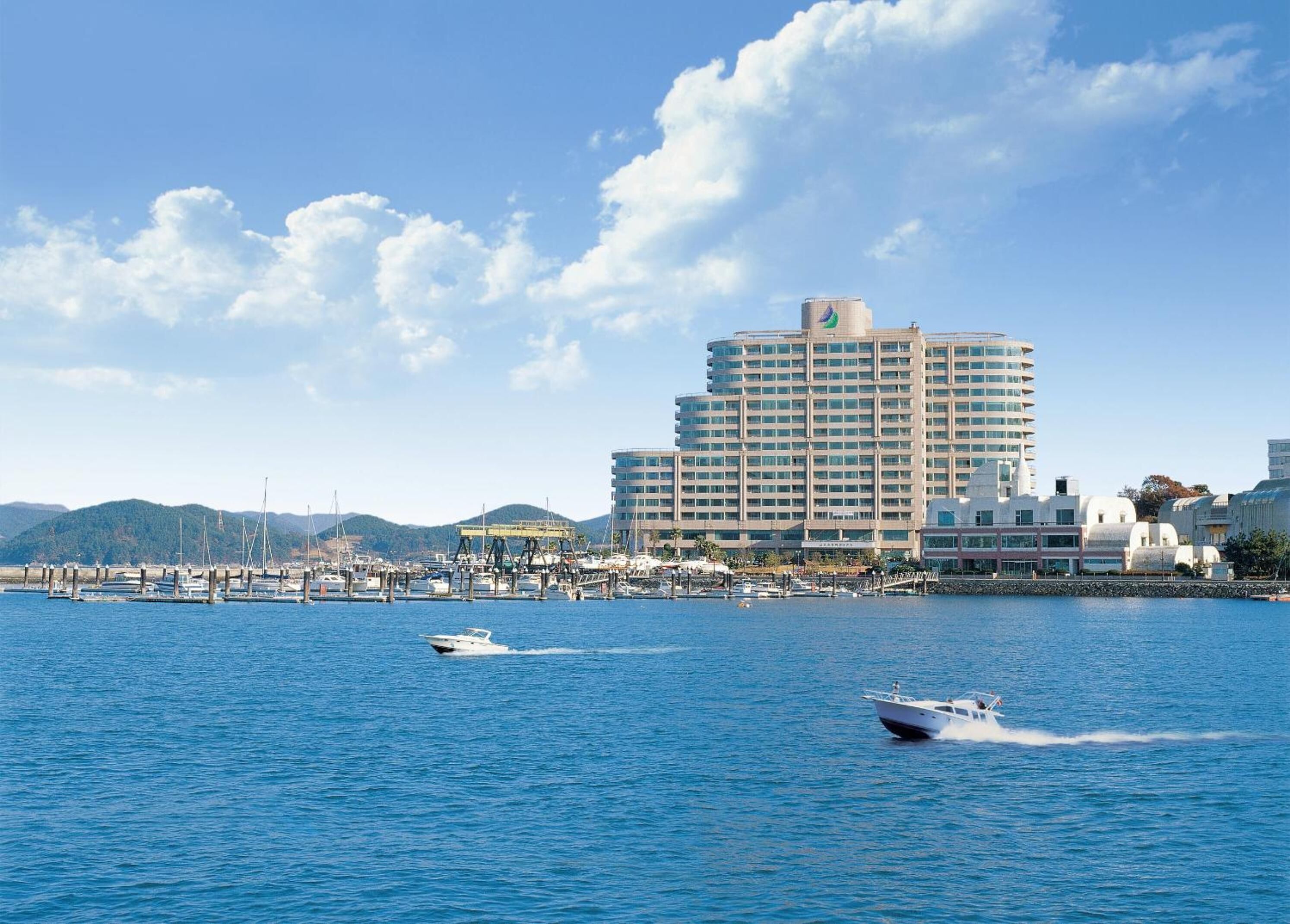 A coastal hotel with a large building, marina, and boats.