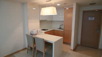 A compact kitchen with a white countertop, a single chair, and a hanging light fixture.
