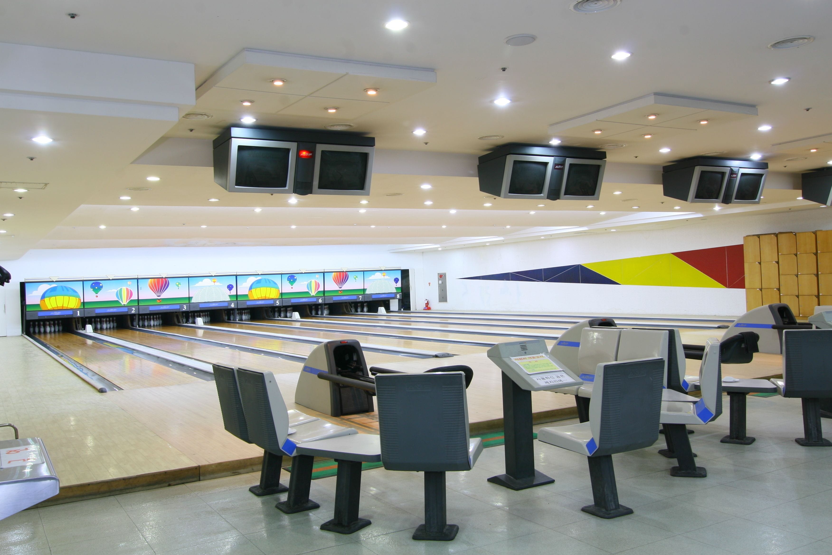 A bowling alley with multiple lanes, overhead televisions, and seating areas.