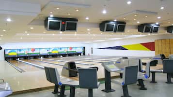 A bowling alley with multiple lanes, overhead televisions, and seating areas.