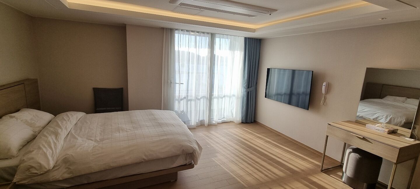Una camera d'albergo con un letto, una scrivania, una televisione e una finestra con tende.