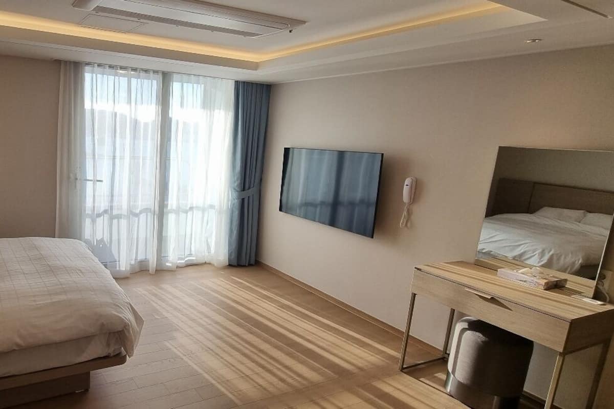 Une chambre d’hôtel avec un lit, un bureau, une télévision et une fenêtre avec des rideaux.