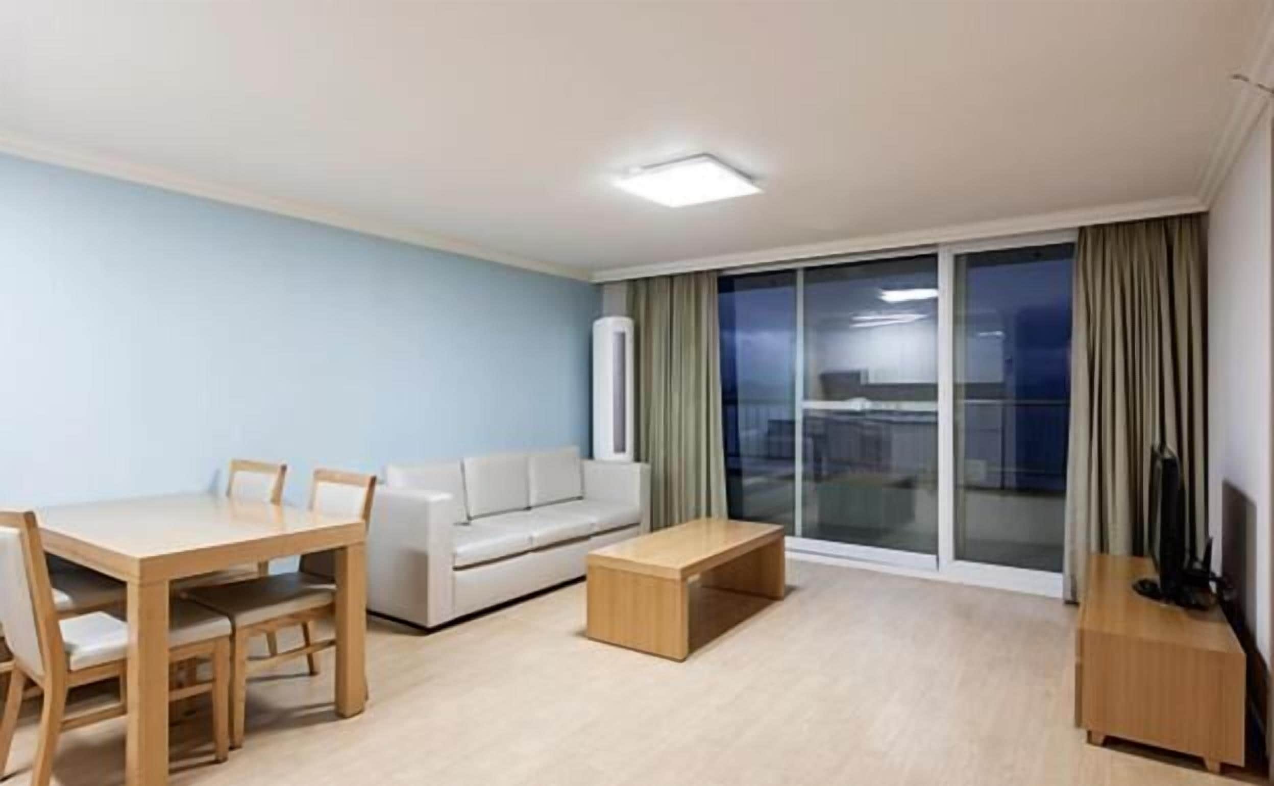 A modern living room with a dining table, sofa, and a small wooden coffee table.