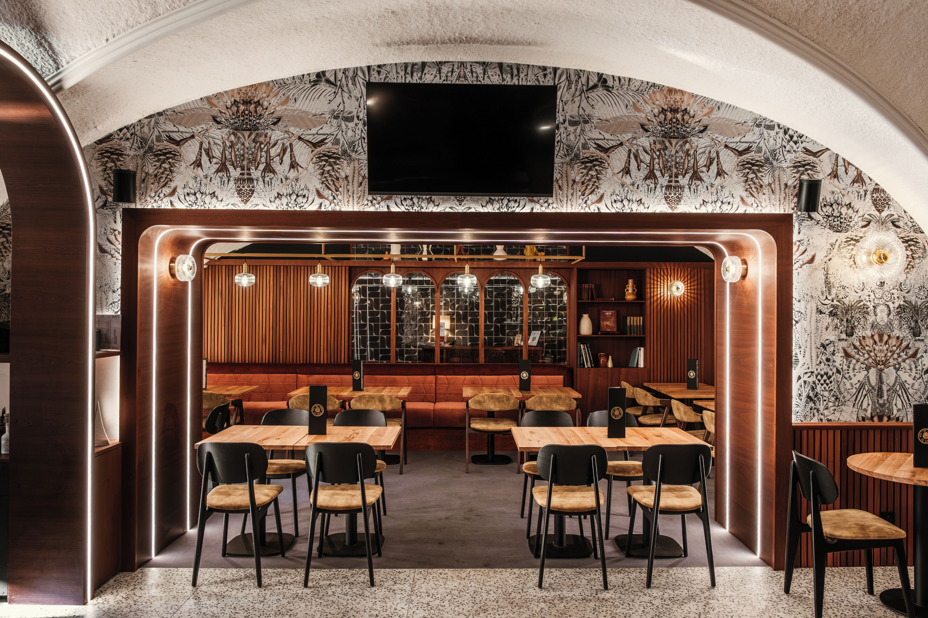 Un ristorante con zona bar, arredi in legno e carta da parati decorata.