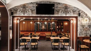 Un ristorante con zona bar, arredi in legno e carta da parati decorata.