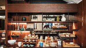 Um buffet de café da manhã com diversos alimentos, uma máquina de café e uma torradeira.