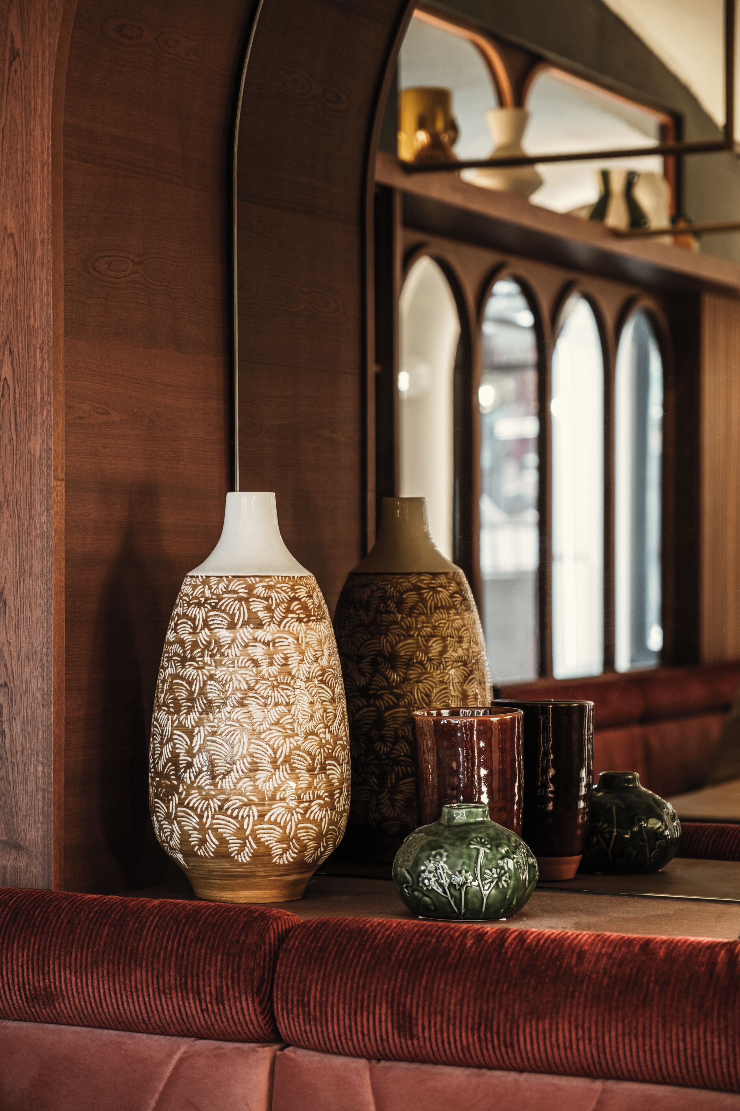 A wooden bench with a vase and a ceramic pot on it.