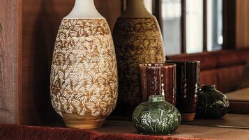 A wooden bench with a vase and a ceramic pot on it.