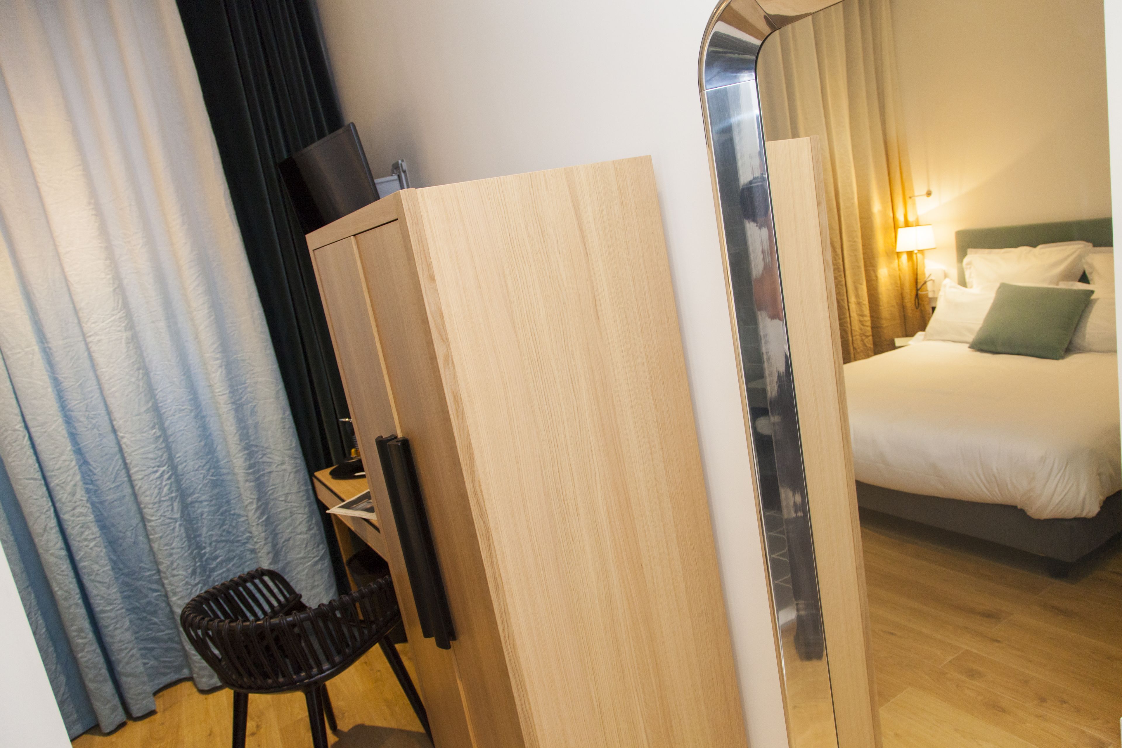 A hotel room with a bed, a desk, a chair, and a wardrobe.