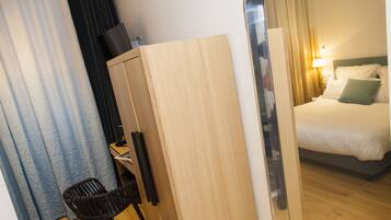 A hotel room with a bed, a desk, a chair, and a wardrobe.