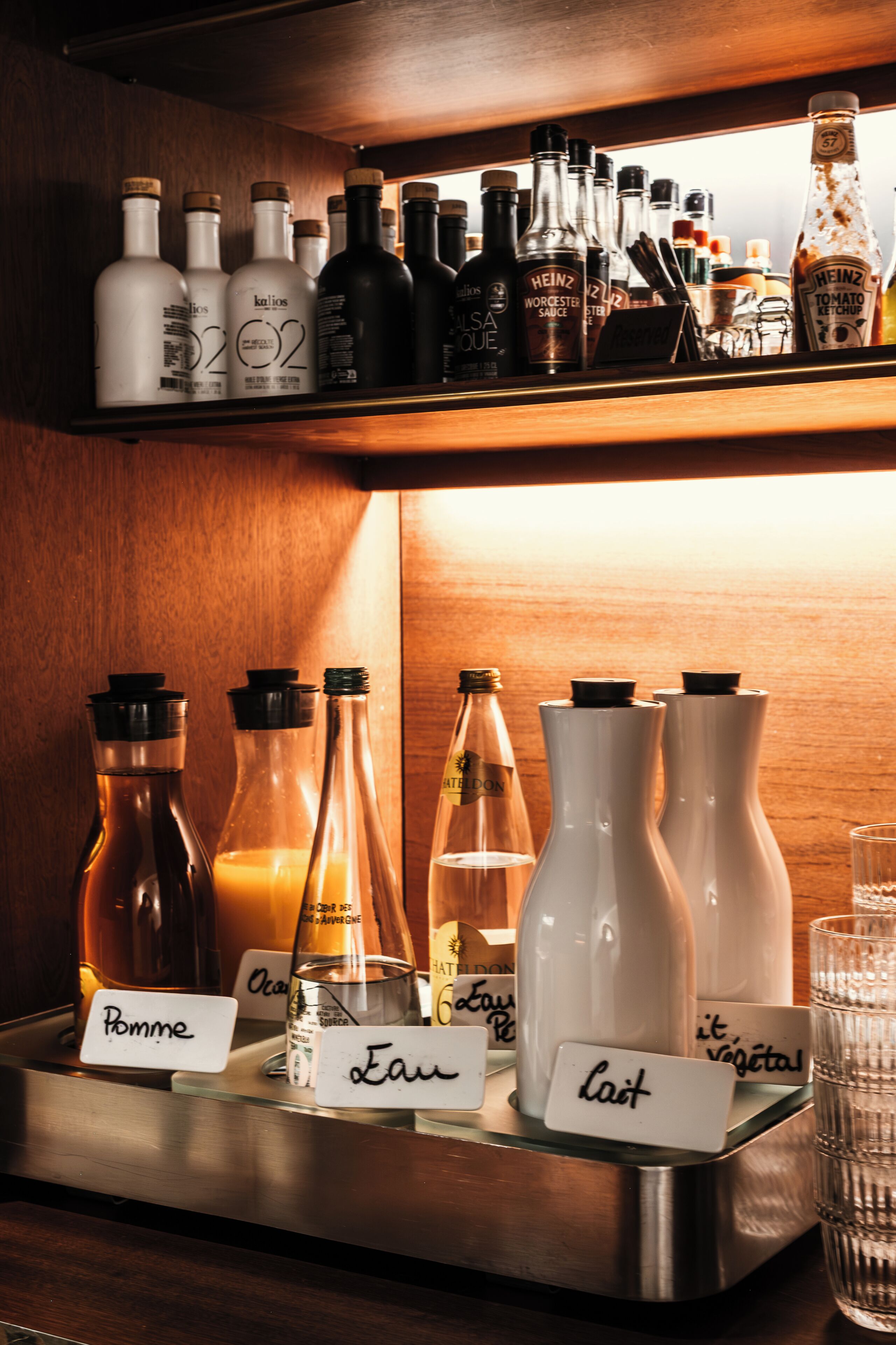 Una zona de bar con varias botellas etiquetadas con nombres como 'Pomme', 'Eau' y 'Lait'.
