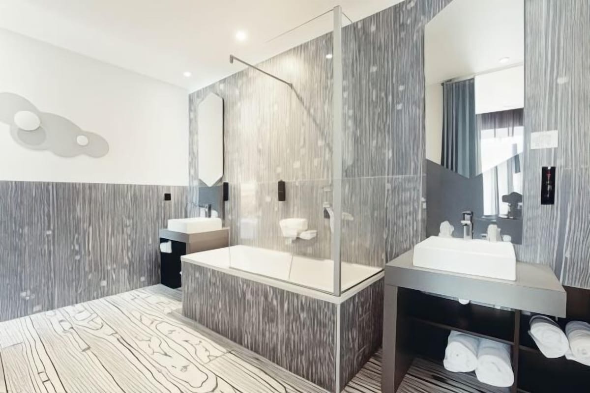 Un baño moderno con dos lavamanos, cabina de ducha de vidrio y un espejo grande.