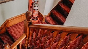 A wooden staircase with red patterned carpet. - Goodwin House (Keswick)