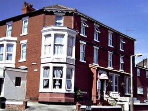 A red brick terraced house with white-framed windows and a bay window on the second floor. - The Marnoch Hotel (Blackpool)