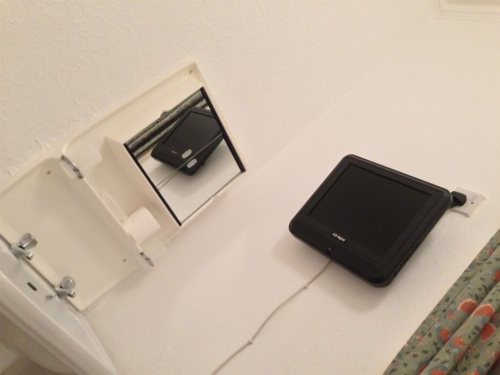 Eine weiße Wand mit einem schwarzen Tablet und einem daran befestigten weißen Gerät.
