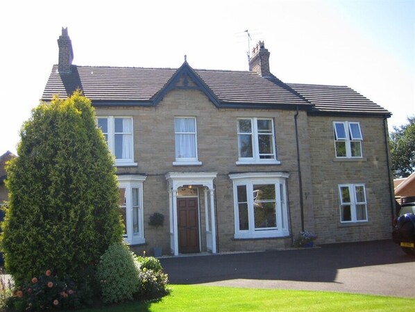 A two-story house with a brick exterior, a pitched roof, and a front entrance with a door and windows.