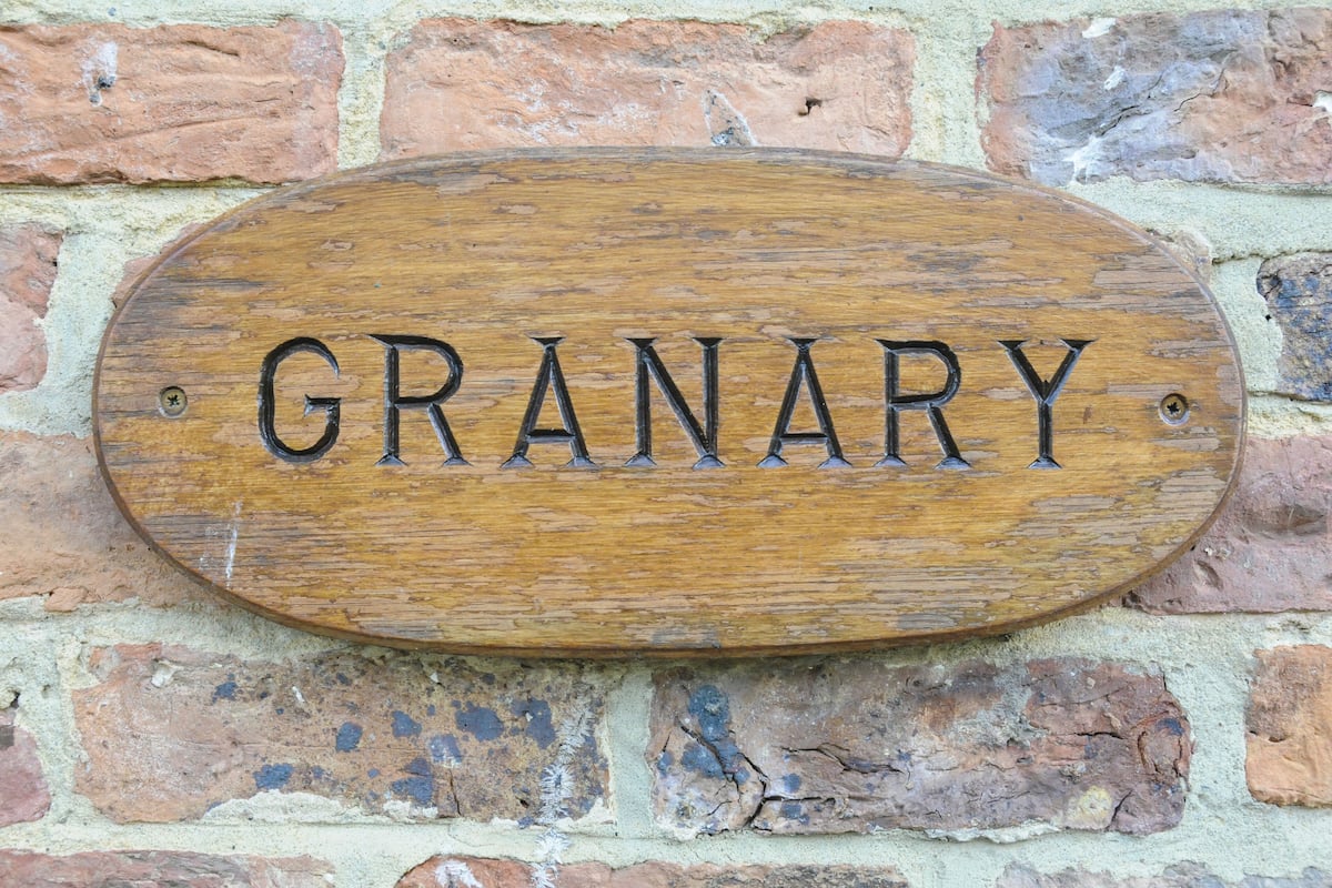 A wooden sign with the word GRANARY on it, mounted on a brick wall.