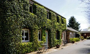 A building covered in ivy with a small outdoor seating area. - The Poplars (Thirsk)
