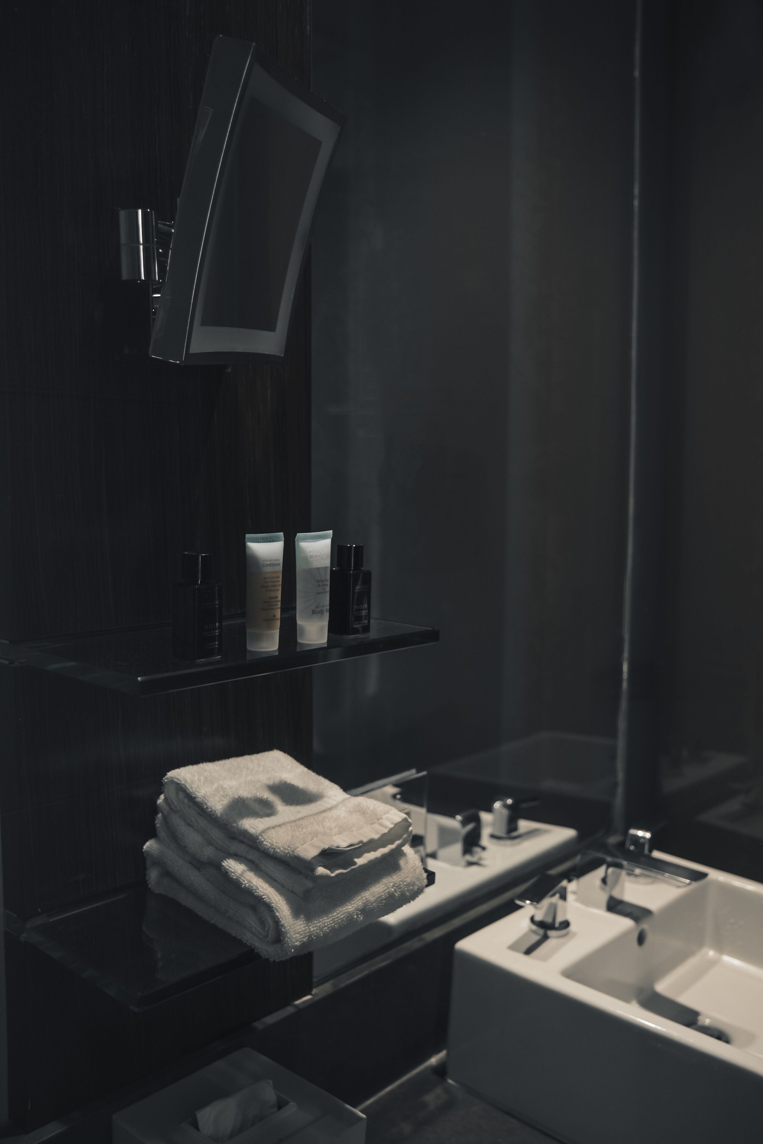 A modern bathroom with a dark wood vanity, a large mirror, and a white sink.