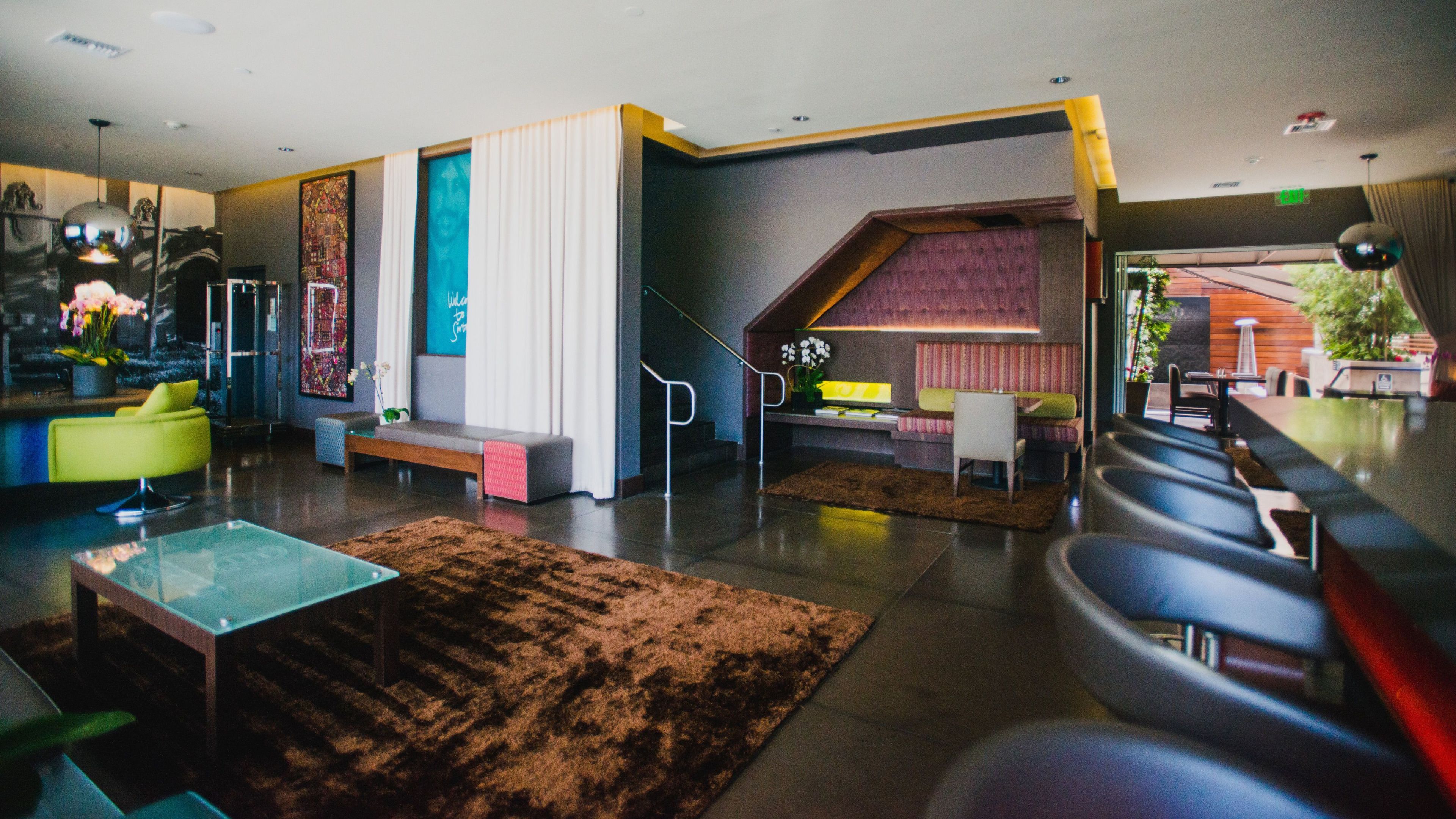 A modern interior with a seating area, a bar, and a staircase leading to a loft.