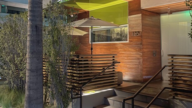 A modern building with a wooden facade, a green awning, and a staircase leading to the entrance. - SIRTAJ - Beverly Hills (Beverly Hills)