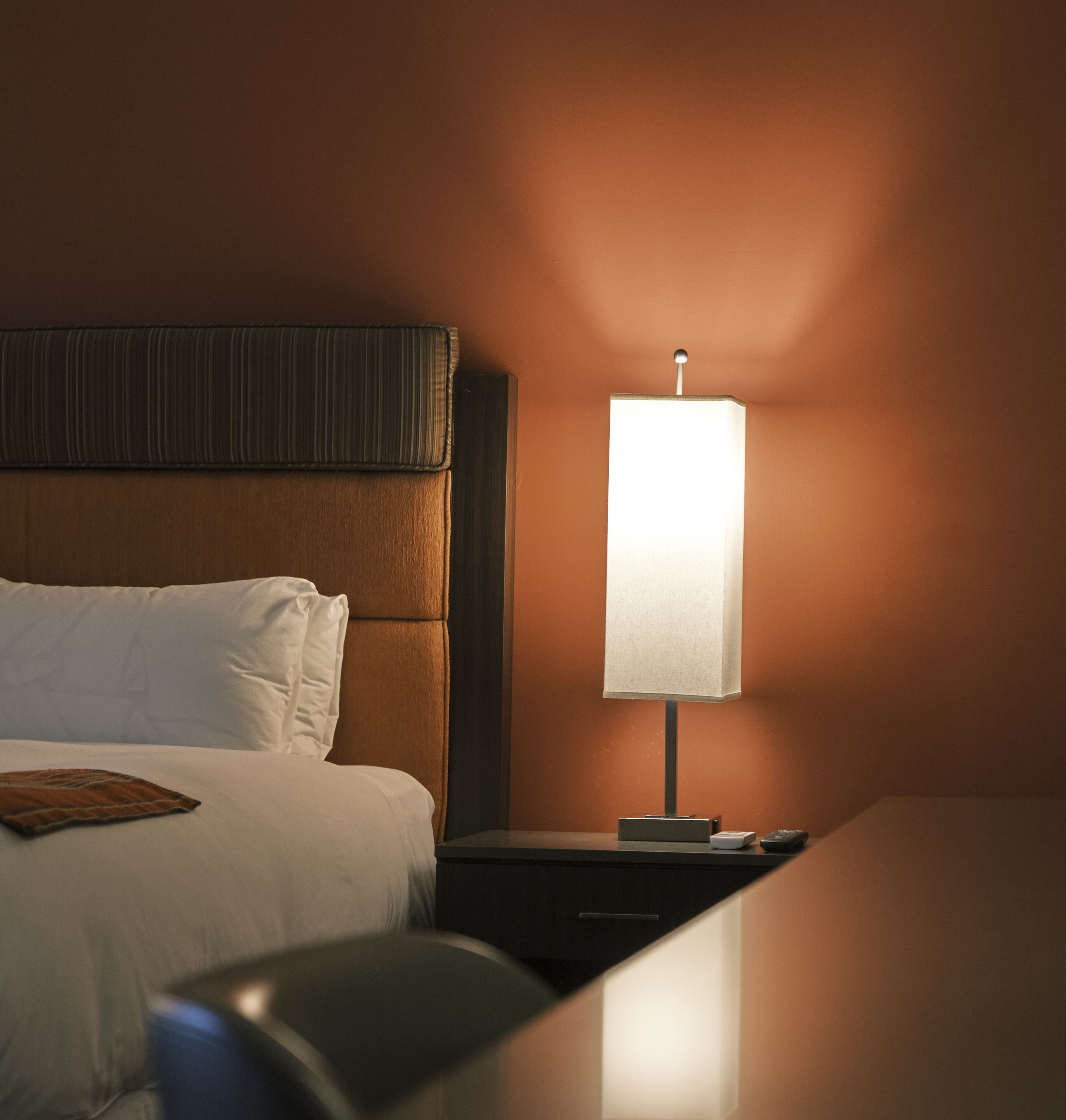A hotel room with a bed, a bedside table, and a nightstand.