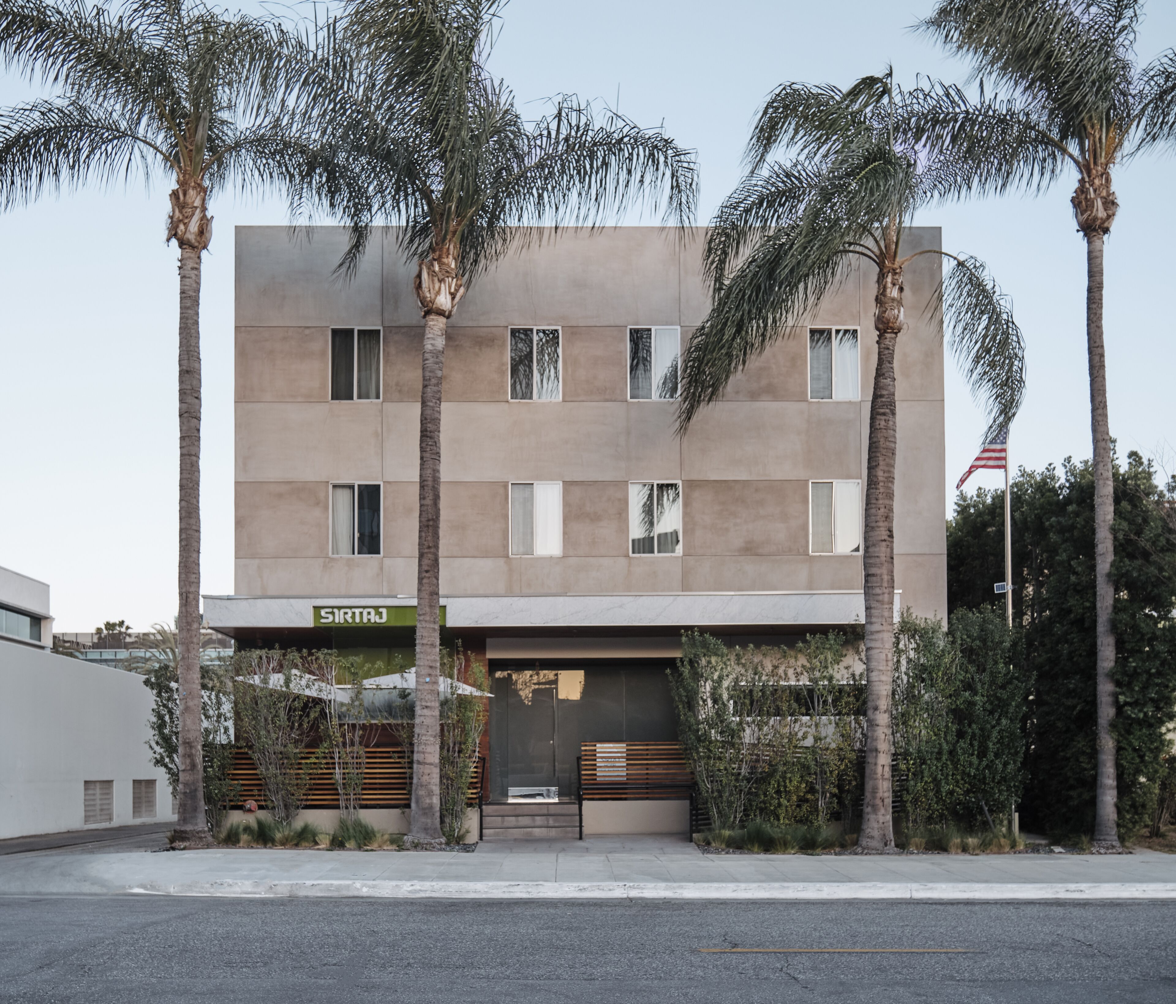 Un edificio moderno con fachada plana, múltiples ventanales y un letrero que dice 