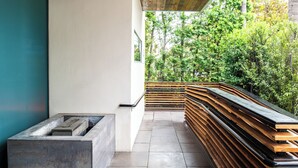 A modern outdoor area with a bench, a planter, and a view of a lush green forest. - SIRTAJ - Beverly Hills (Beverly Hills)