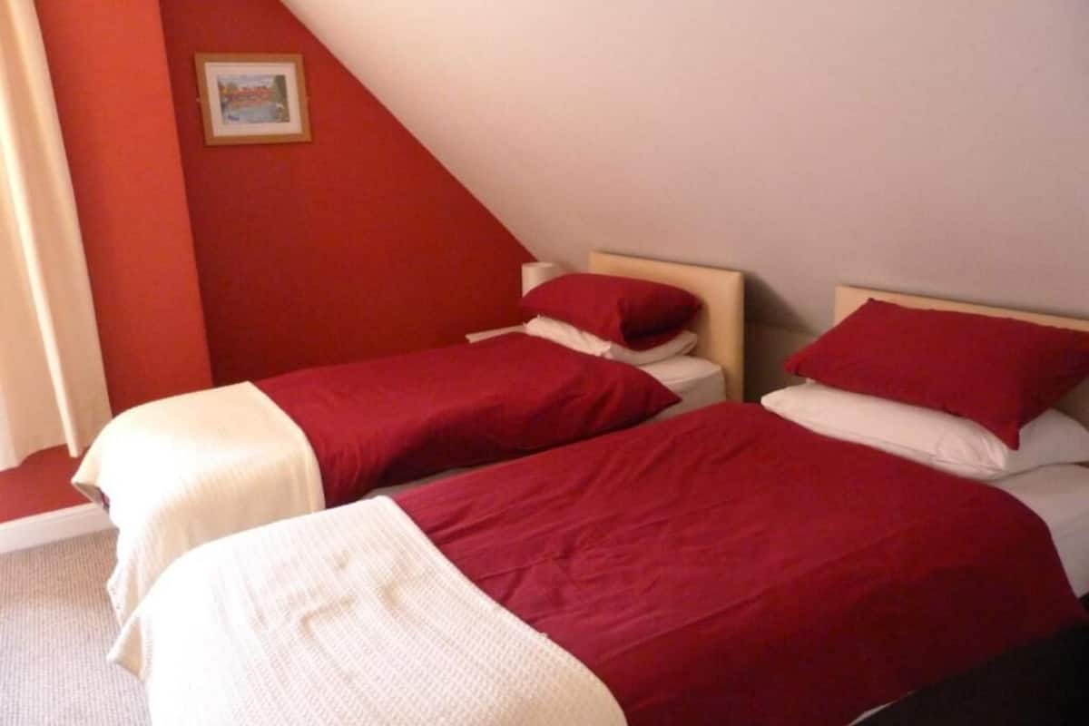 A room with two beds, each with red bedding and white pillows.
