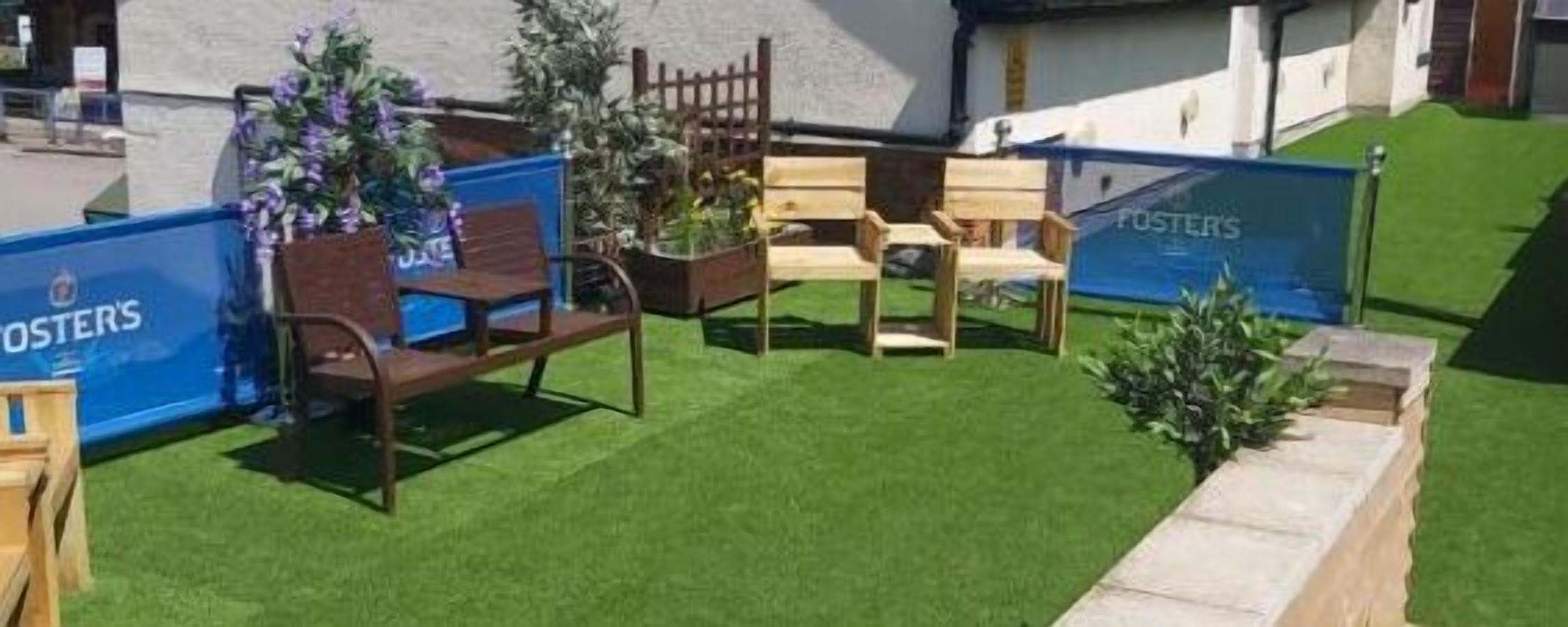 Un espacio exterior con mobiliario de madera y un pequeño jardín.