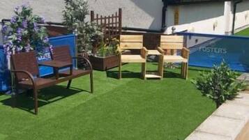 Un espacio exterior con mobiliario de madera y un pequeño jardín.