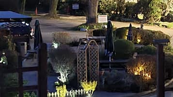 A nighttime view of a landscaped garden area with pathways, benches, and illuminated plants.