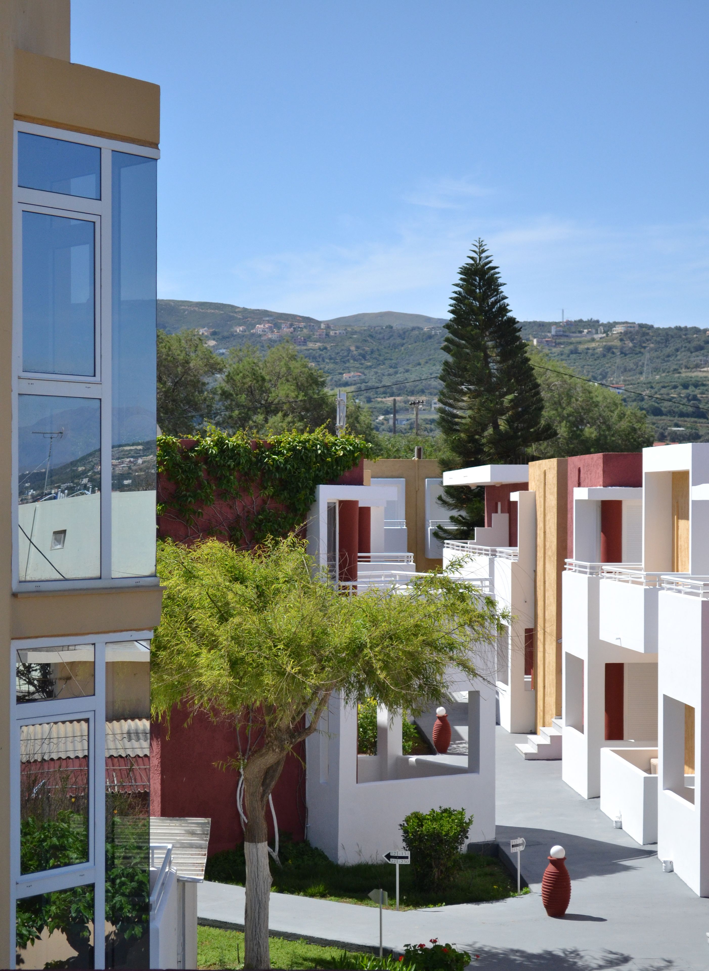 A modern building with multiple balconies and a view of the surrounding hills.