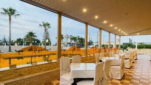 Un área de comedor al aire libre con piso a cuadros, manteles blancos y sillas.